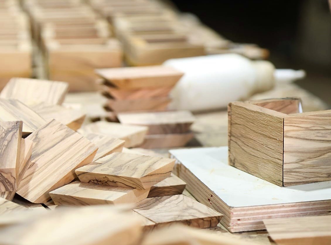 Hand-cut olive wood pieces and a box being assembled in a Holy Land workshop